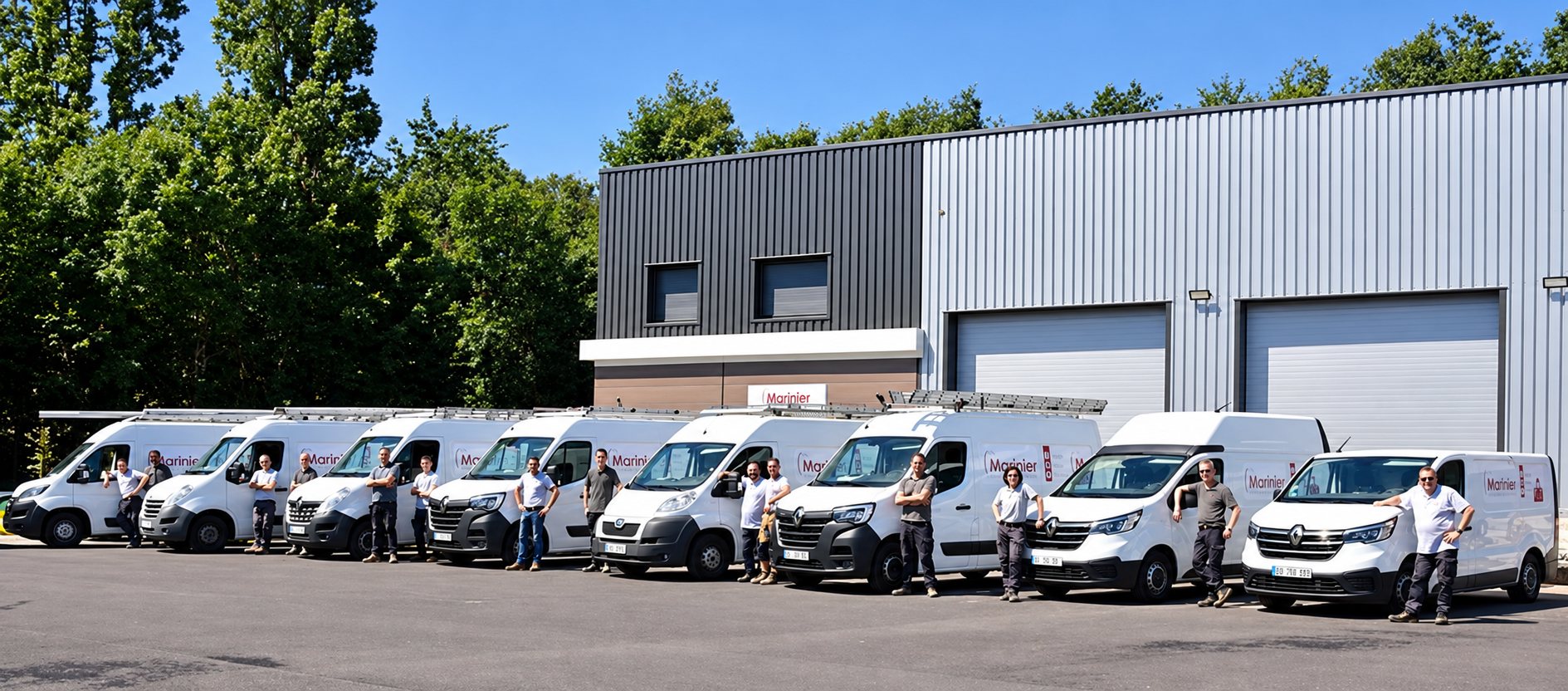 L’équipe Marinier posant devant une flotte de camionnettes blanches à l’entrepôt.